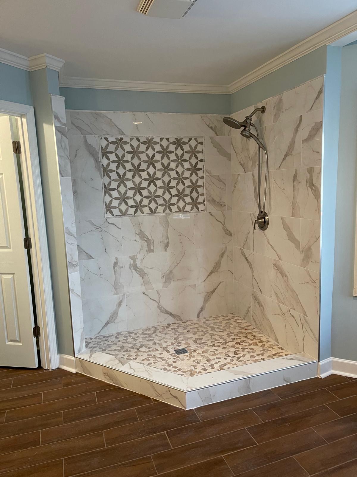 Marble tile shower with mosaic niche